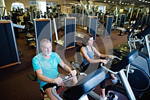 Beautiful fit senior couple in gym doing cardio work out.