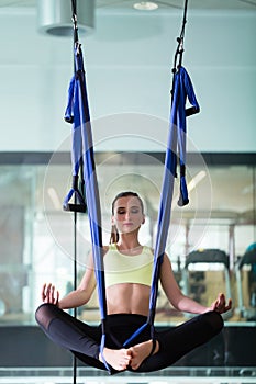 Beautiful fit woman meditating while hanging in lotus position