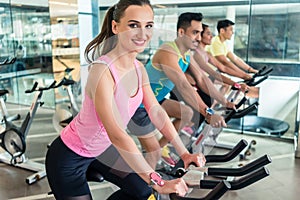 Beautiful fit woman smiling during cardio workout at indoor cycl