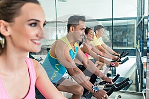 Beautiful fit woman smiling during workout at indoor cycling group class