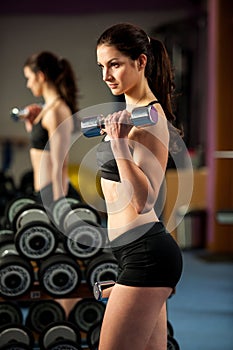 Beautiful fit woman works out with dumbbells in a fitness gym