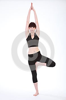 Beautiful fit woman in Yoga Tree Pose Vrksasana