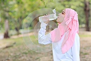 Beautiful fitness athlete asian muslim woman drinking water after work out exercising. Young cute girl standing in sportswear
