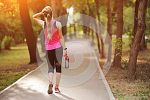 Beautiful fitness athlete runner woman drinking water in the park. Water bottle