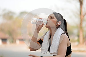 Beautiful fitness athlete woman drinking water after work out exercising on sunrise morning summer in park