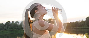 Beautiful fitness athlete woman drinking water after workout exercising on sunset evening summer in beach outdoor