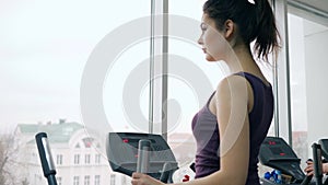 Beautiful fitness girl exercising on simulator in gym