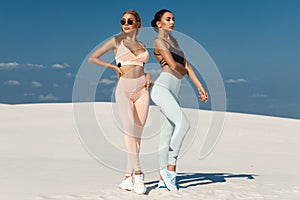 Beautiful fitness models in sportswear. Couple athletic girls in leggings outdoor photo