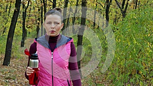 Beautiful fitness sport girl walking along the autumn park in sportswear with sports water bottle or isotonic drink in