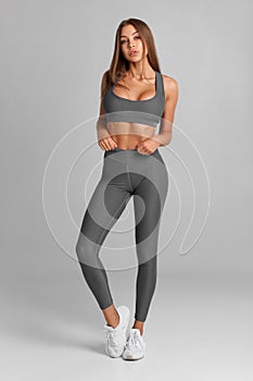 Beautiful fitness woman. Athletic girl on the gray background