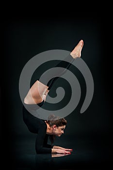 beautiful fitness woman doing stretching exercise on black background Hands Standing Upside Down