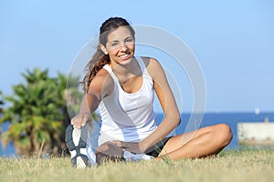 Beautiful fitness woman stretching outdoor on the grass