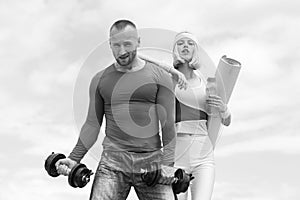 Beautiful fitness young sporty couple with dumbbell and sports inventory over sky background. Young athlete woman