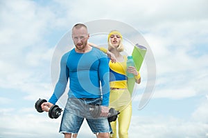 Beautiful fitness young sporty couple with dumbbell and sports inventory over sky background. Young athlete woman