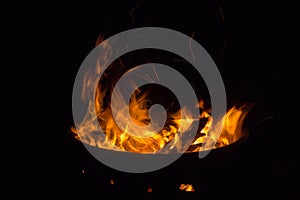 Beautiful flame with sparks in bonfire in the night. Heat and danger energy concept. Fire on black background.
