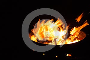 Beautiful flame with sparks in bonfire in the night. Heat and danger energy concept. Fire on black background.