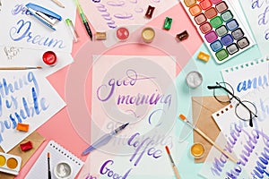 Beautiful flatlay arrangement with watercolors, brushes, glasses, brushpen, paints with good morning handlettering and other stati photo