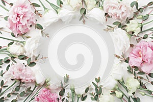 Beautiful floral frame of pastel flowers and eucalyptus leaves on white table top view. Flat lay style. photo