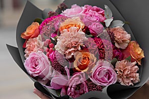 Beautiful flower bouquet with roses, cloves in hands. Florist. Flower shop Pink and orange flowers.