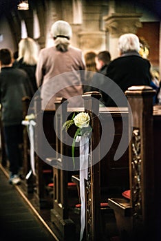 Beautiful flower wedding decoration in a church hang on the seat rows setting in the Chapel, ceremony selective focus