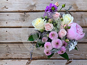 Beautiful flowers arrangement with peony and rose on a rustic wooden background.