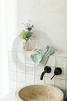 Beautiful flowers bouquet in modern marble sink in stylish bathroom. Summer flowers arrangement gathered from garden in modern