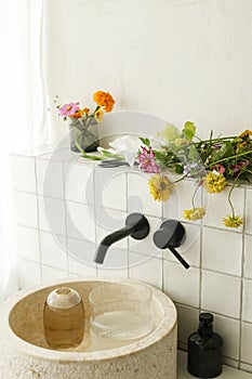 Beautiful flowers bouquet in modern marble sink in stylish bathroom. Summer flowers arrangement gathered from garden in modern