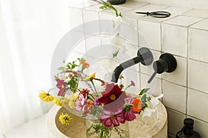 Beautiful flowers bouquet in modern marble sink in stylish bathroom. Summer flowers arrangement gathered from garden in modern