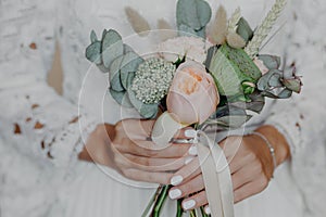 Beautiful Flowers in brides hands. Bridal bouquet. Woman in wedding white dress prepared for wedding ceremony. Selective focus