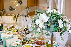 Beautiful flowers on elegant dinner table in wedding day. Decorations served on the festive table in blurred background