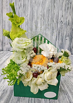 Beautiful flowers in an envelope. Luxurious bouquet with flowers and fruits