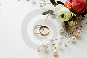 Beautiful  flowers, pearl jewelry and two gold wedding rings on a white background. Marriage concept. Wedding bouquet. Isolated