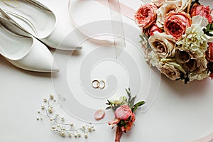 Beautiful  flowers, pearl jewelry and two gold wedding rings on a white background. Marriage concept. Wedding bouquet. Isolated