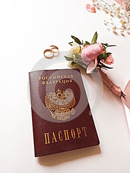 Beautiful flowers, pearl jewelry and two gold wedding rings on a white background. Marriage concept. Wedding bouquet with passport