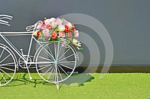 Beautiful flowers on pillion of white bicycle beside the wall