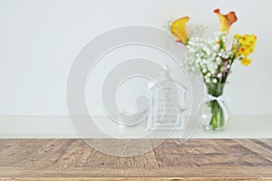 Beautiful flowers in the vase in front of wooden empty table. Ready for product display presentation.