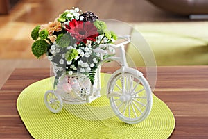 Beautiful flowers in a white bicycle on wooden table