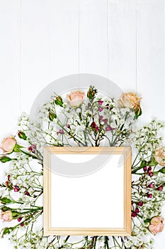 Beautiful flowers and wooden photo frame on white wooden table.