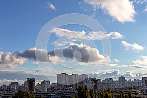 Beautiful fluffy cumulus clouds in the light blue sky above the city