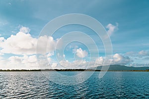 Beautiful, fluffy white clouds form white reflections in the rippled blue water of a bay along the Oregon coast