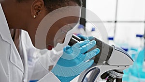Beautiful, focused african american woman scientist working meticulously with a microscope in a professional lab, engrossed in her