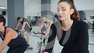 Beautiful focused woman cycling on spin bike at cycling class