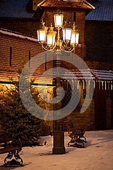 A beautiful forged lantern shines at night, illuminating a beautiful street.