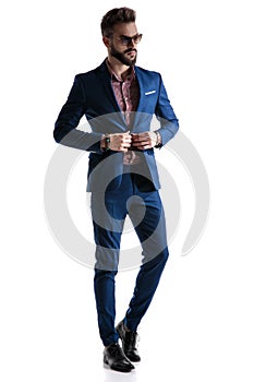 Formal businessman in blue suit fixing coat