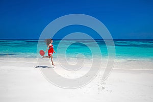 Beautiful free young woman jumping on the exotic sea, happy brunette girl in red dress running on tropical beach with white sand.