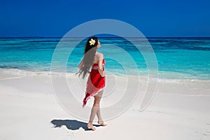 Beautiful free young woman relax on the exotic sea, brunette smiling girl in red dress on tropical beach with white sand.