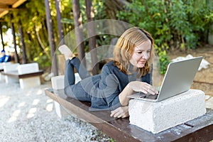 A beautiful freelancer woman works at the park using a computer