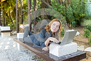 A beautiful freelancer woman works at the park using a computer