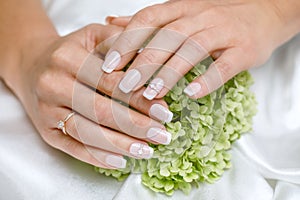 Beautiful French manicure in pink and white with rhinestones for the bride. Close-up nails. Wedding accessories.