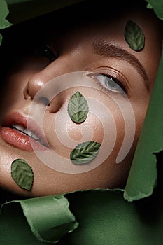 Beautiful fresh girl with perfect skin, natural make up and green leaves. Beauty face. Close up